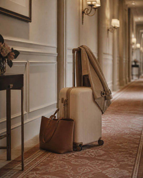Trolley da cabina color crema nel corridoio di un hotel: il bagaglio a mano perfetto